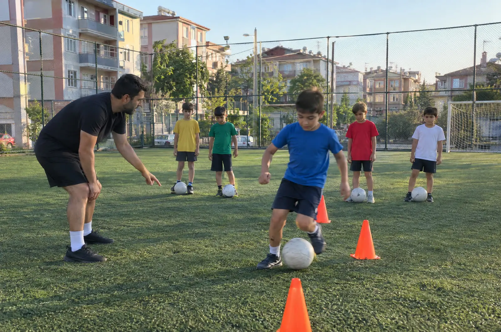 Sahada antrenörüyle futbol çalışan çocuk